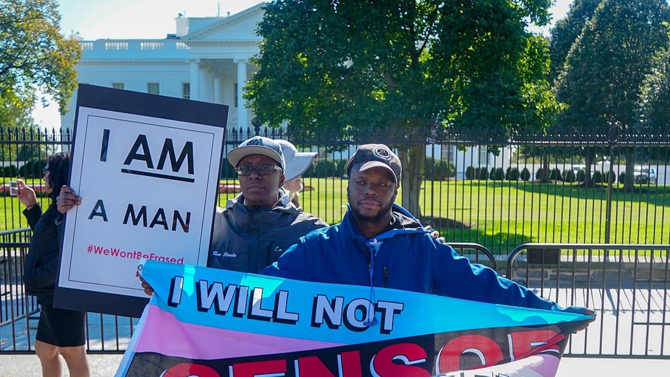 Two protesters hold signs at a rally for trans rights