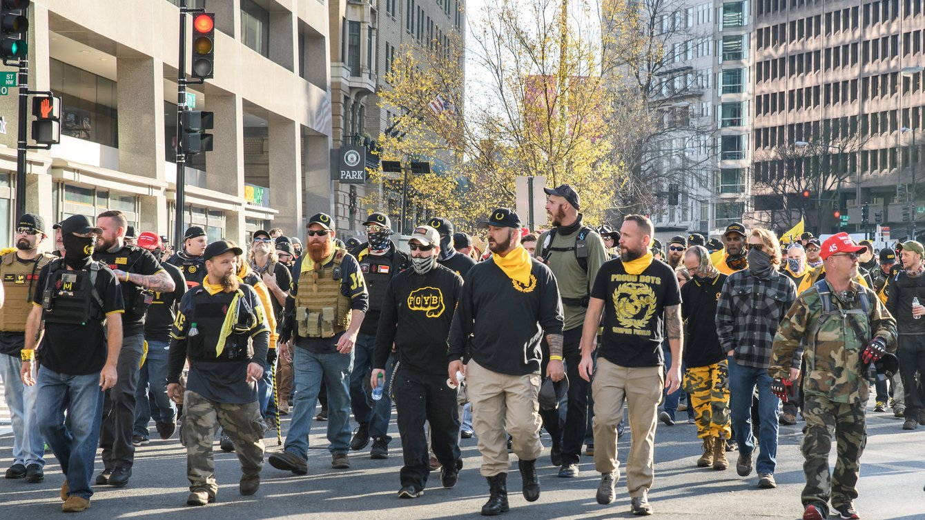 A group of men, in Proud Boys gear walking on a street.