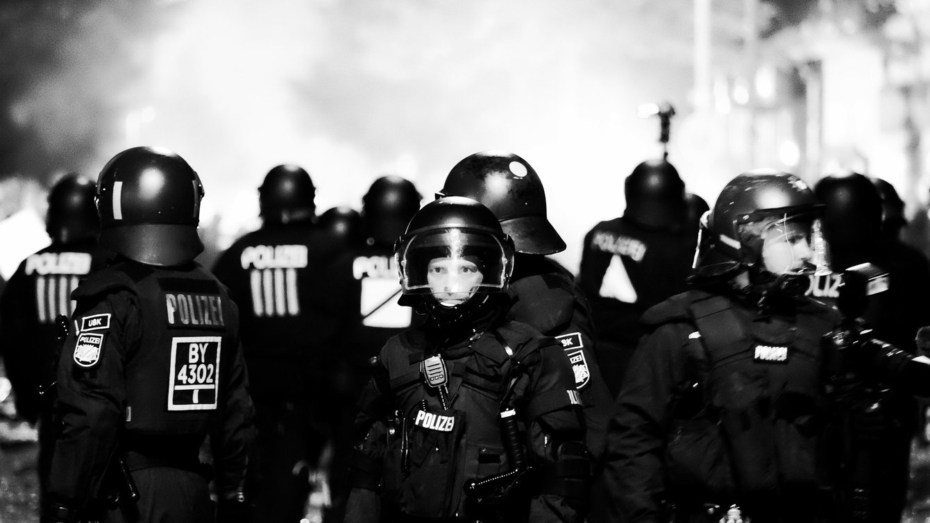 A group of men in german police gear wearing helmets. One man is looking straight at the camera.