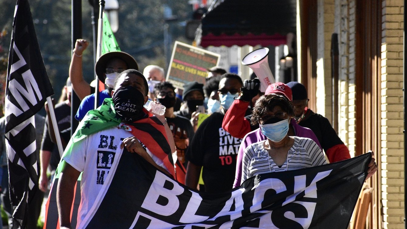 Protesters holding a black lives matter flag and walking
