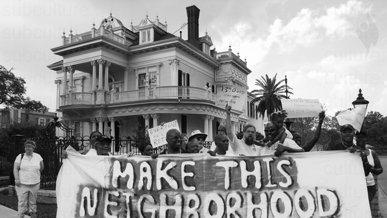 Protesters holding a sign that says "Make this neighborhood mixed income"