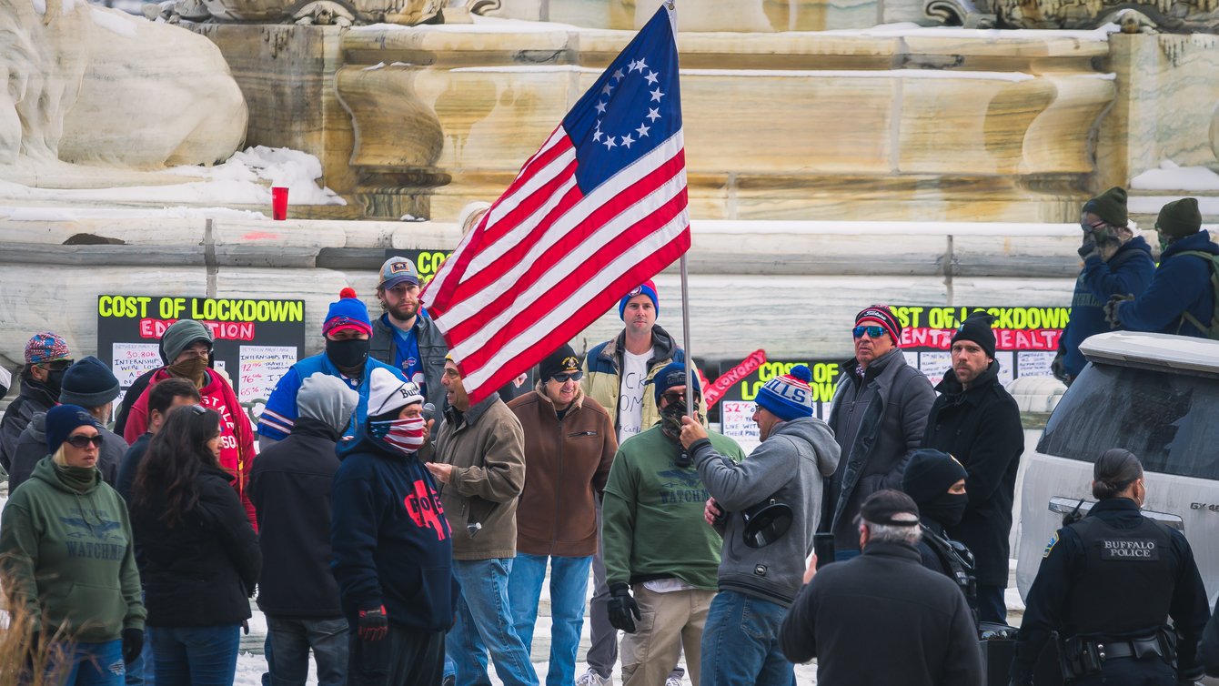 Crowd wearing winter clothes holding colonial American flag