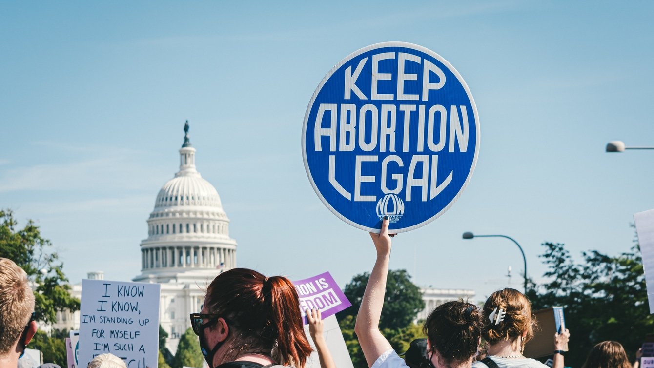 A protester in front of the Capitol holding a sign that says "Keep Abortion Legal"