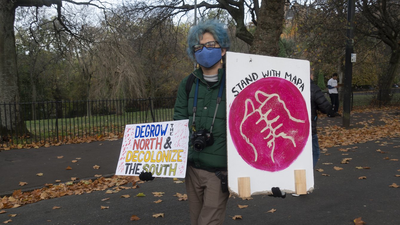 A person at a protest holding a sign that says DeGrow the North and Decolonize the south