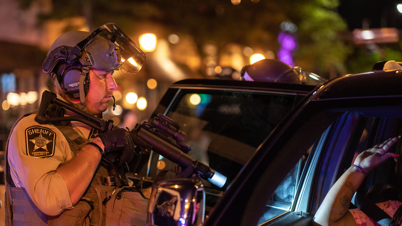 A sheriff pointing a gun at a car.