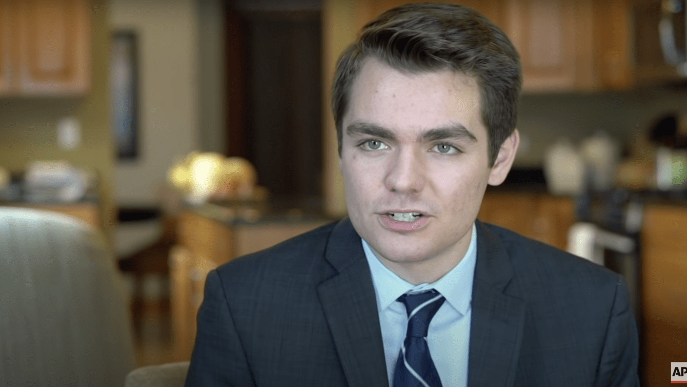 A young white man, Nick Fuentes, in a suit