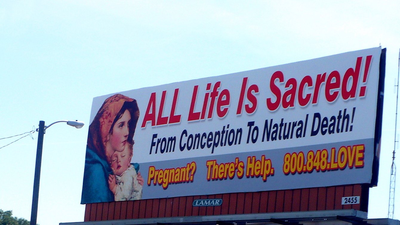 a billboard that says "All life is Sacred! From conception to natural death! Pregnant? There's Help. 800.748.LOVE"