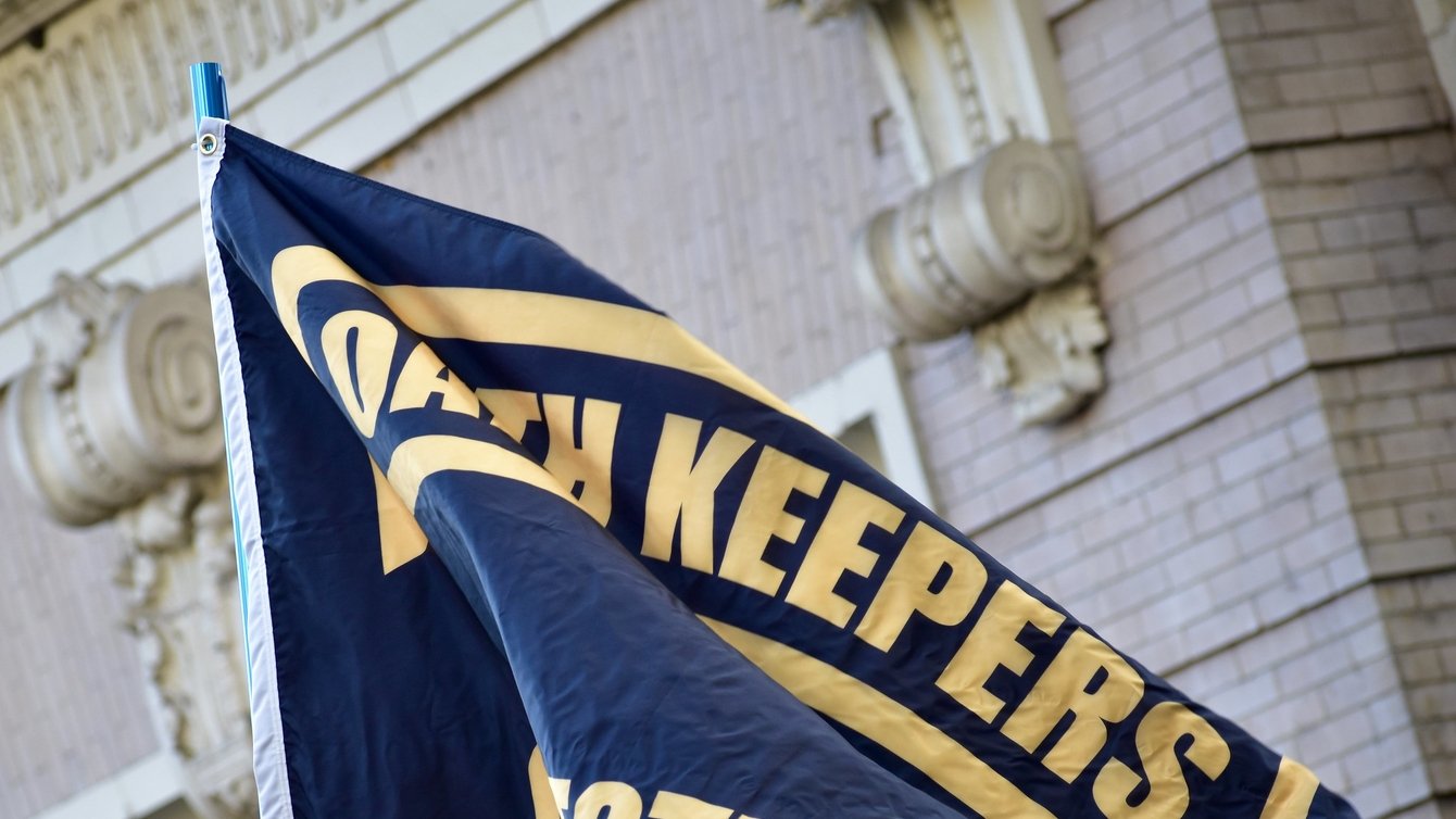 A black flag with the Oath Keepers logo in yellow printed on it.
