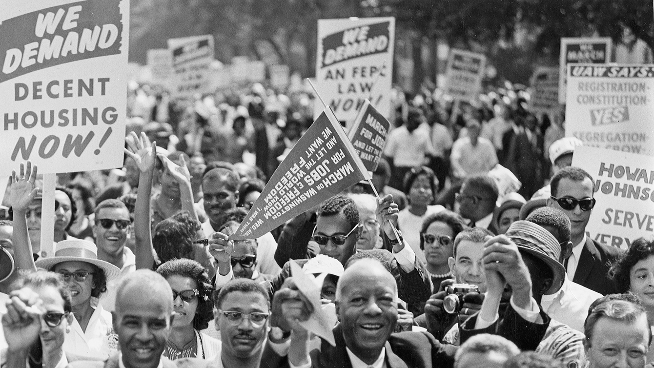 a group of people marching, holding signs.