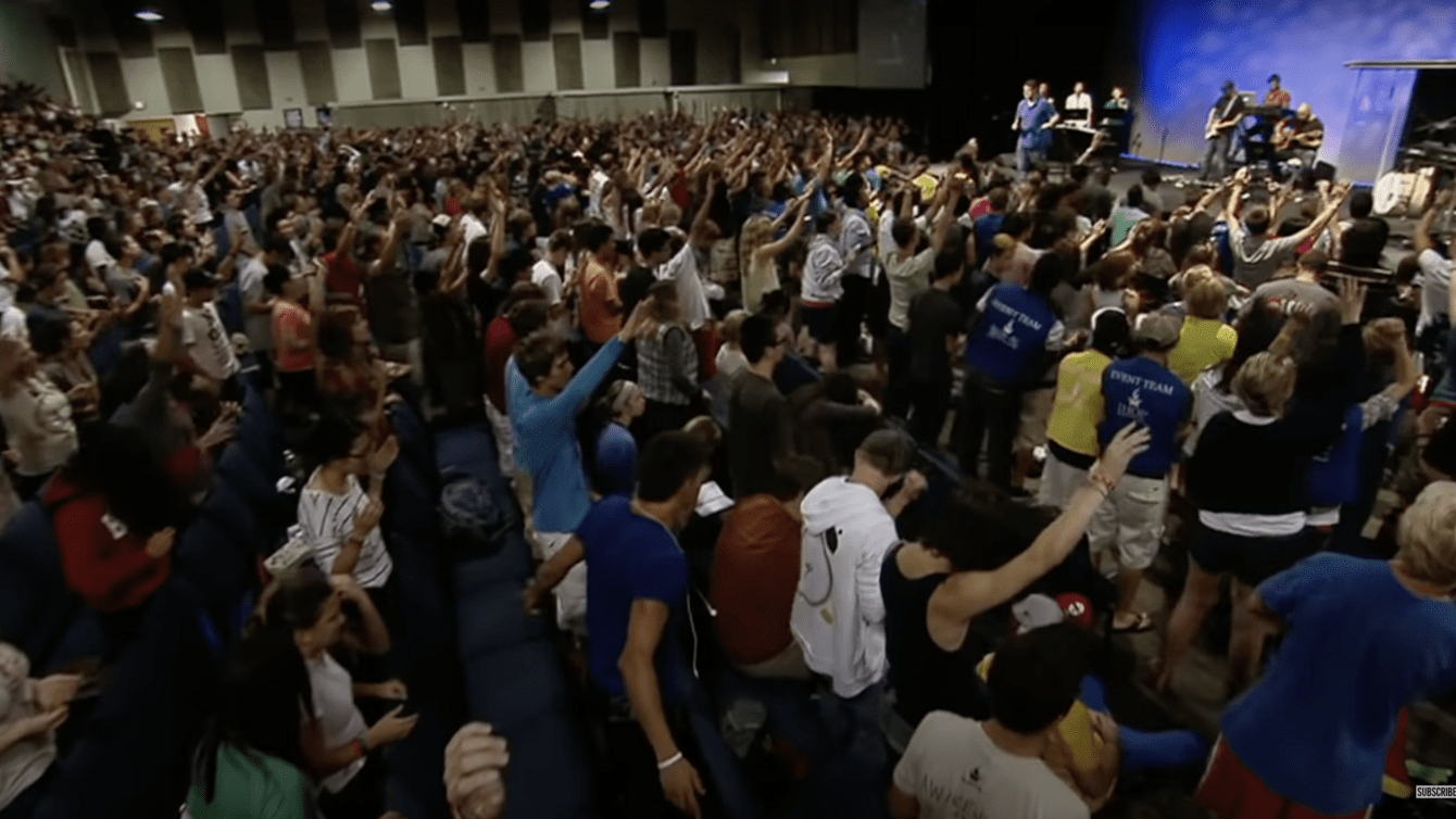 A group of people in a room with their hands raised.