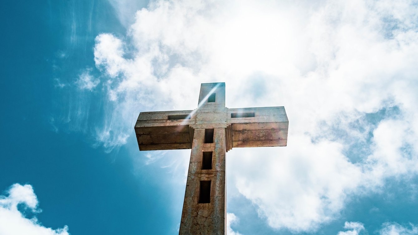 A wooden cross against a blue sky.