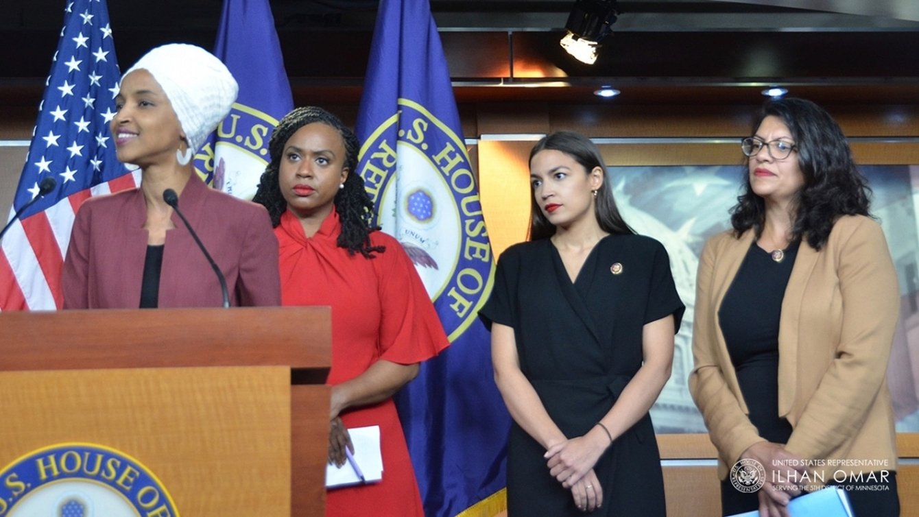 A woman standing in front of a podium with three women behind her.