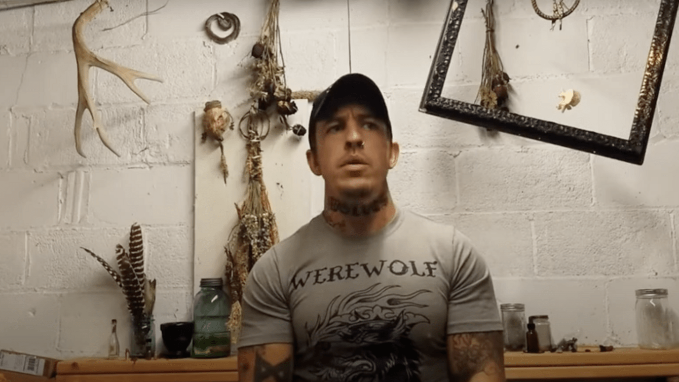 A man in a grey t shirt with hunting memorabilia in the background