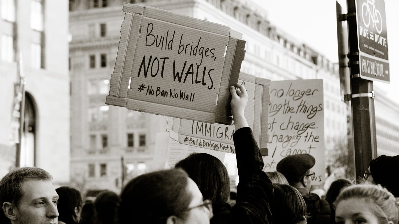 A protestor holding a sign that says "build bridges not walls"