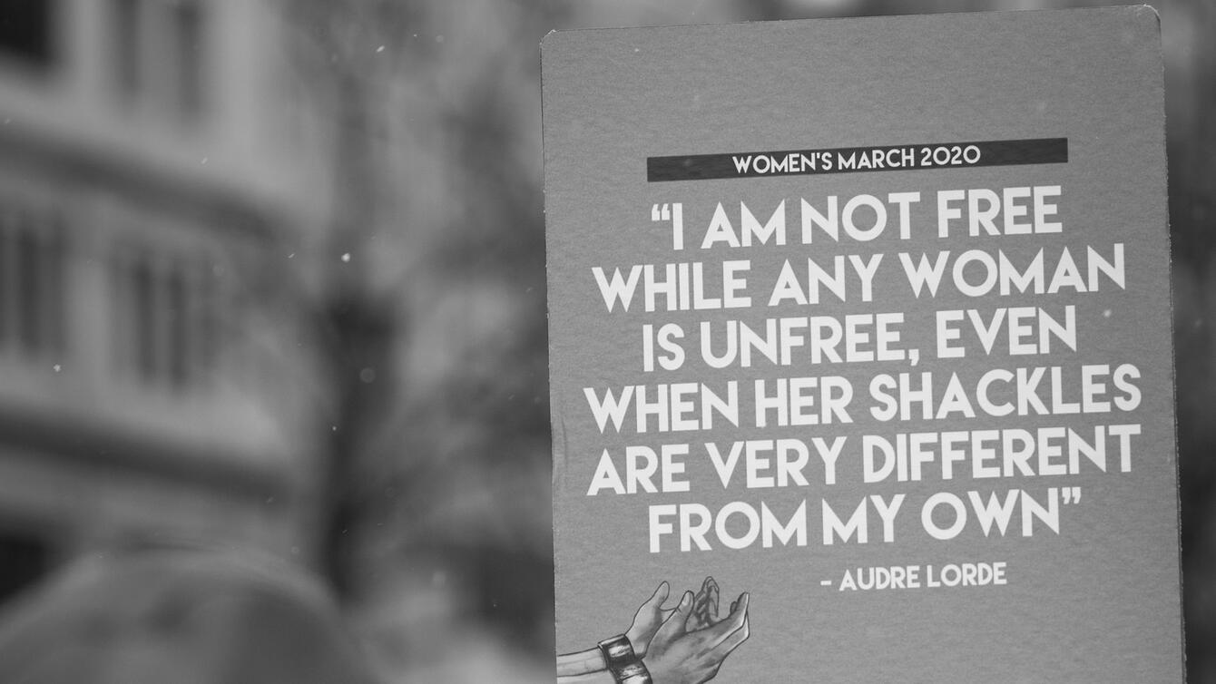 A sign that reads "I am not free while any woman is unfree, even when her shackles are very different from my own" - Audre Lorde