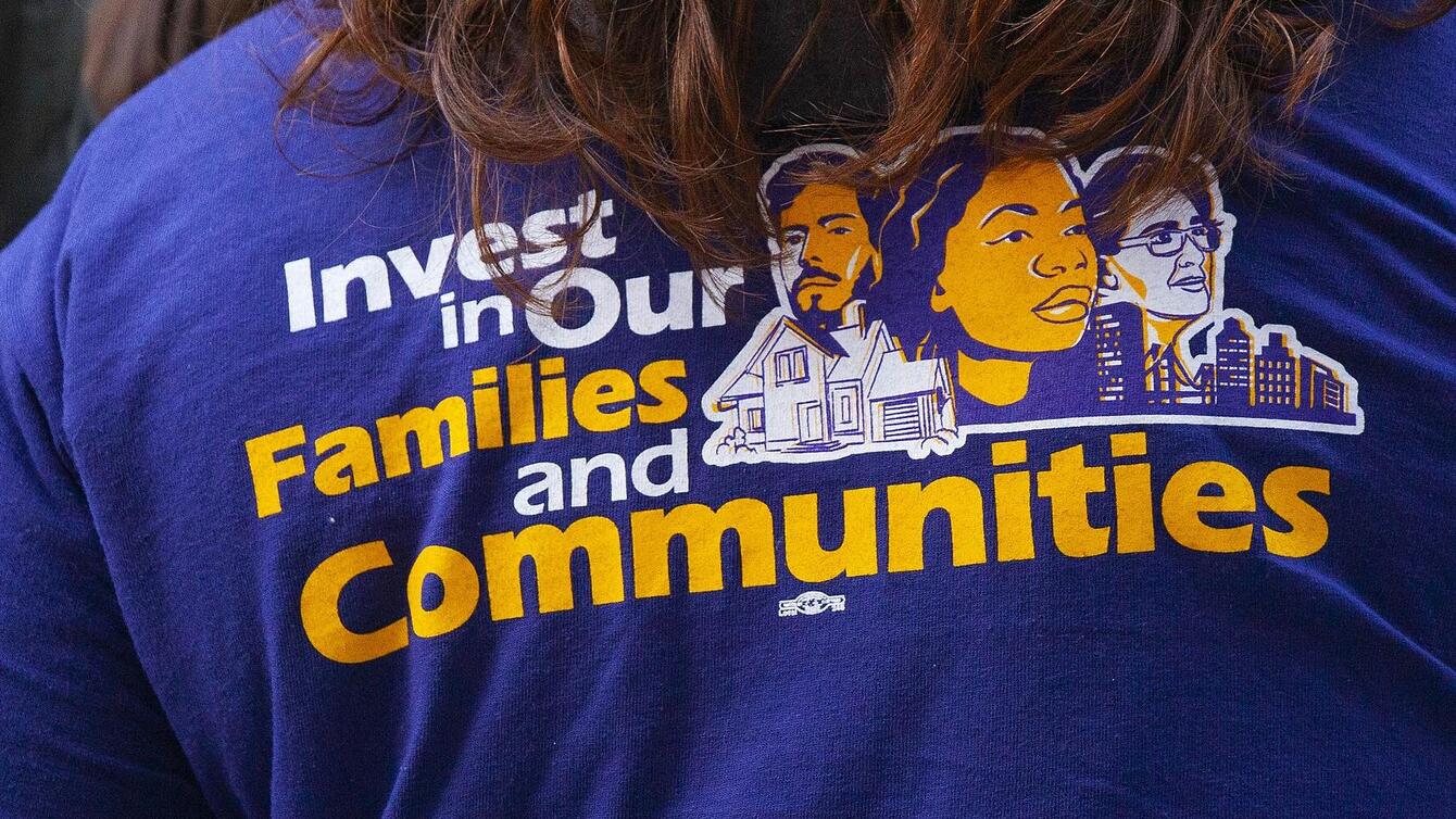 A T-shirt that reads "Invest in our families and communities"