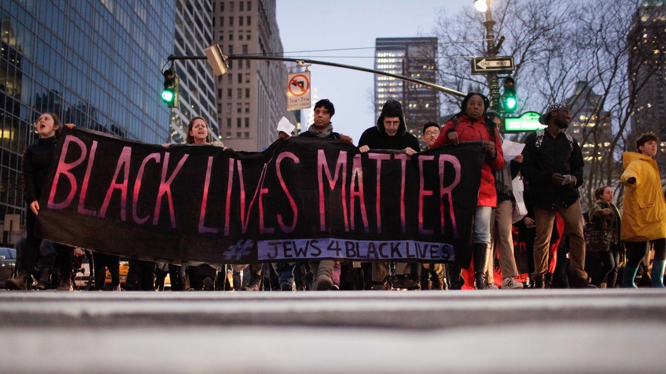 A group of people holding a banner that reads "Black Lives Matter Jews 4 Racial Justice"