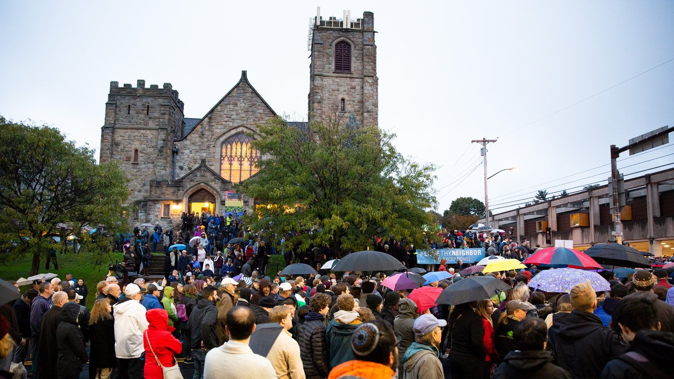 People gathered in front of a stone synagogue