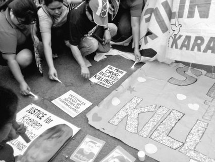 people kneeling with candles with signs on the floor.