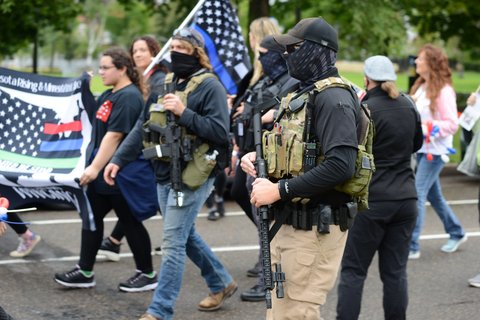 Armed militia members march next to a WWG1WGA flag, a common identifier of QAnon believers, at the United We Stand & Patriots March for America, St. Paul, Minnesota, September 12, 2020 (Credit: Fibonacci Blue/Flickr).