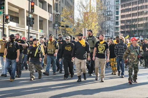 A group of men, in Proud Boys gear walking on a street.