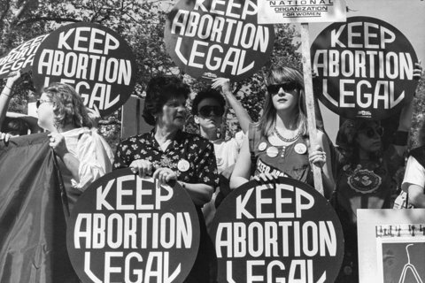 White women protesting, holding circular signs that say "Keep Abortion Legal"