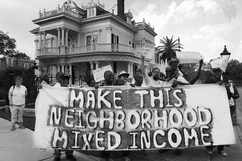 Protesters holding a sign that says "Make this neighborhood mixed income"