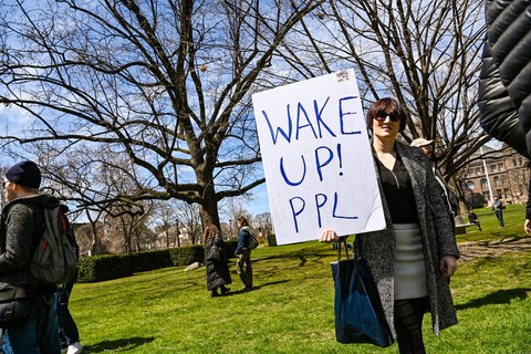 A woman holding a sign saying "Wake up! Ppl"