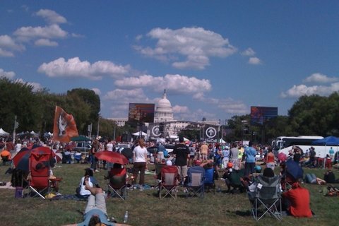 People standing in a field sporadically in front of the D.C capitol
