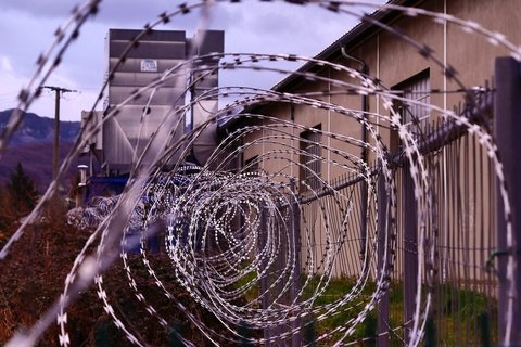 Barbed wire in a spiral form outside a brown building.