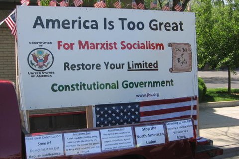 A sign that says "America is too great for marxist socialism. Restore your limited. Constitutional Government. www.jbs.org"