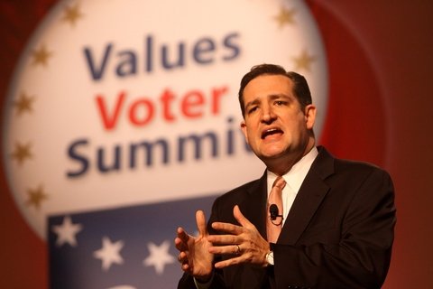 A man in the middle of a speech in a suit with "Values Voter Summit" in the background.