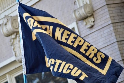 A black flag with the Oath Keepers logo in yellow printed on it.