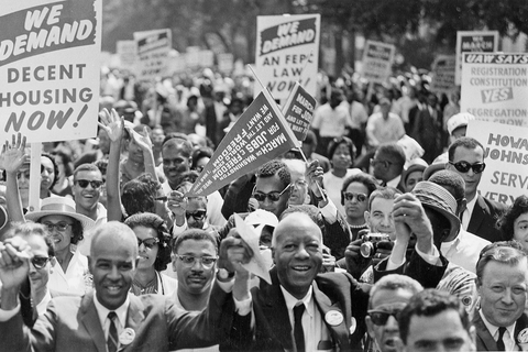 a group of people marching, holding signs.