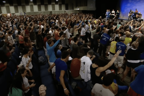 A group of people in a room with their hands raised.