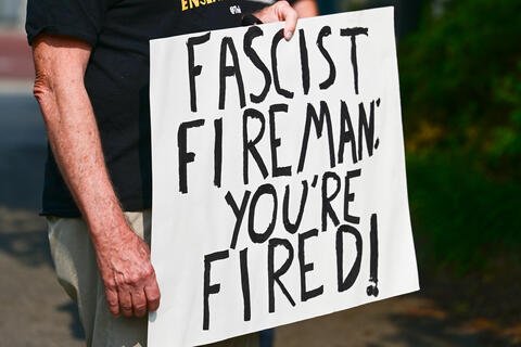 a sign that says "Fascist Fireman: You're Fired!"