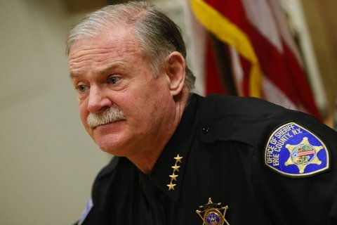 A man with white hair and white mustache in a sheriff's uniform.