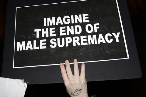 A black sign with the words "imagine the end of male supremacy"