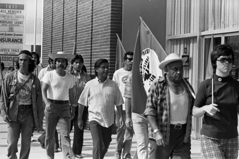 a black and white image of men holding flags walking.