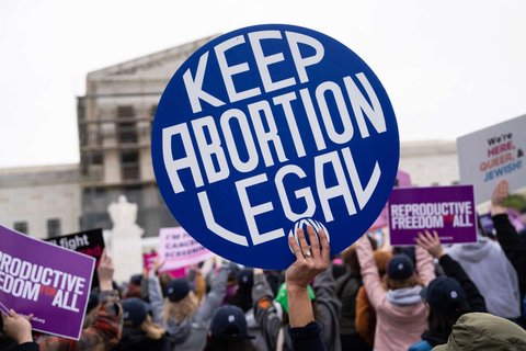 a hand holding a sign that reads "Keep Abortion Legal"