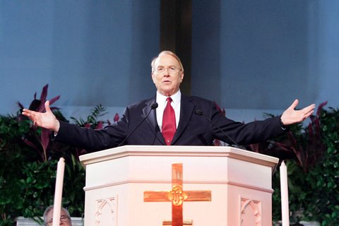 A man standing behind a podium with a cross