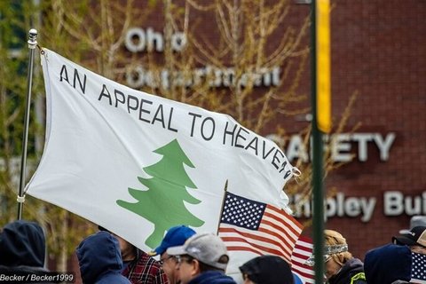 Man in a crowd holding an Appeal to Heaven flag