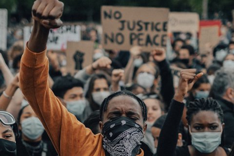 a group of people in masks with a person in the foreground with their fist up in the air
