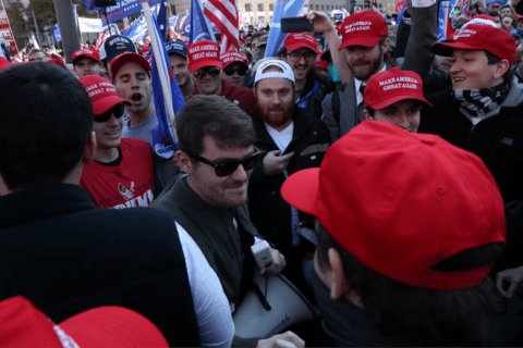 Nick Fuentes surrounded by people in MAGA hats