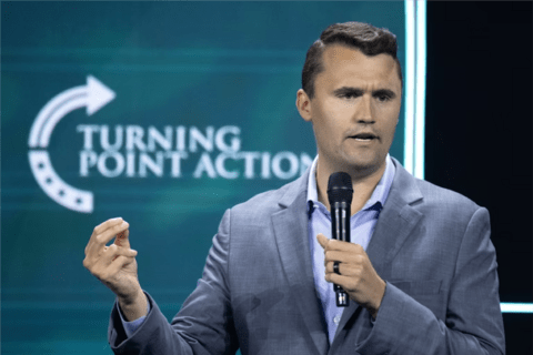 a man in a grey suit with a Turning Point Action background