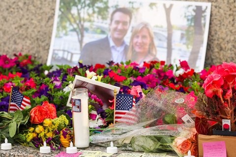 candles, flowers and US flags in front of a picture of a man and a woman
