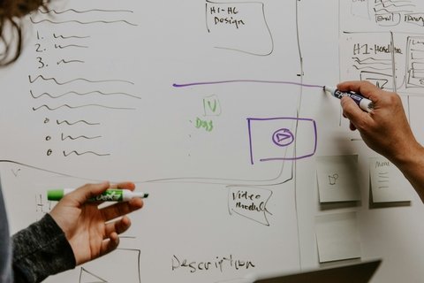 A white board with a person drawing on it and another person holding a pencil