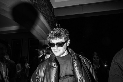 a black and white image of a man in a jacket and sunglasses